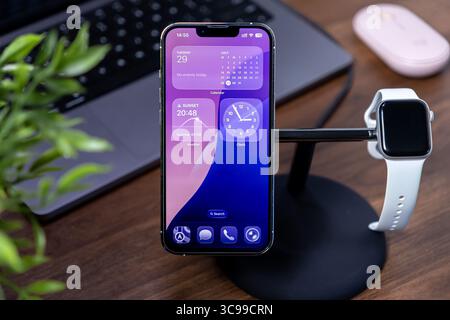 Poznan, Polen – 29. Juli 2025: Visualisierung von ios 26 Liquid Glass auf einem iPhone und Demonstration eines modernen Smart-Device-Setups für vernetzte Produktivität Stockfoto