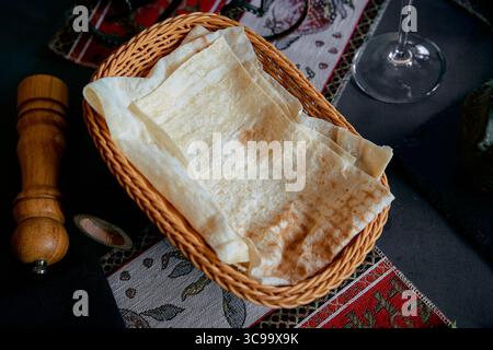 Eine Nahaufnahme eines traditionellen Korbs gefüllt mit frisch zubereiteten Fladenbroten, perfekt für ein köstliches Essen Stockfoto