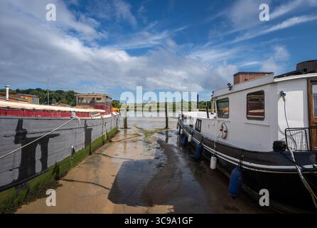 Boote sitzen auf Schlamm in der Sonne. Blick auf den Kai bei Ebbe am Fluss Deben in der historischen Stadt Woodbridge in Suffolk, Großbritannien. Stockfoto