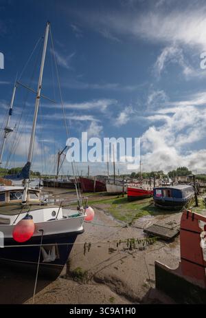 Woodbridge, Suffolk, Großbritannien: Boote sitzen an einem sonnigen Tag auf Schlamm. Blick auf den Kai bei Ebbe auf dem Fluss Deben in der historischen Stadt Woodbridge. Stockfoto