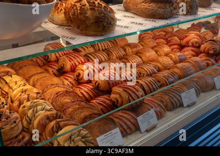Französische Backwaren, darunter Pain au Chocolate, Pain au Praliné und Pain aux Rosinen, die in einem Schaufenster in Paris liegen Stockfoto