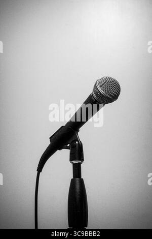 Schwarzweißfoto von kabelgebundenem dynamischem Mikrofon auf dem Ständer, minimalistisch Stockfoto