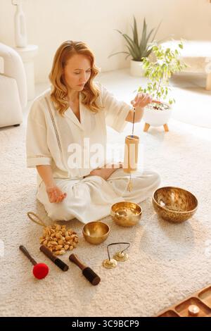 Frau mit Koshi-Glockenspiel während der Meditation und des Klangheilungsrituals für Wohlbefinden und Entspannung zu Hause Stockfoto