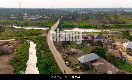 Aus der Vogelperspektive einer kurvenreichen Straße, die durch die Landschaft führt, mit Blicken auf den Fluss und verstreute Gebäude, Yenegoa, Bayelsa, Nigeria. Stockfoto