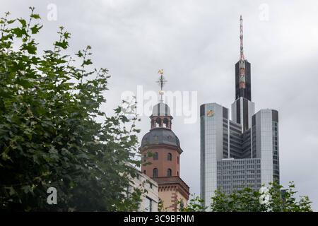 Commerzbank Tower und Katharinenkirche in Frankfurt 05.08.25, Frankfurt: Symbolfoto, Illustrationsbild, Symbolbild, Illustrationsfoto, Alltagsszene Blick auf den Commerzbank Tower in Frankfurt am Main mit seiner markanten Antennenspitze. Davor ragt der Turm der Katharinenkirche mit goldener Wetterfahne empor. Im Vordergrund verdecken Baumkronen teilweise die Sicht, was der Aufnahme eine natürliche Rahmung verleiht. Frankfurt Hessen Deutschland *** Commerzbankturm und Katharinenkirche in Frankfurt 05 08 25, Frankfurt Symbolfoto, Illustrationsfoto, Symbolfoto, Illustrationsfoto, E Stockfoto