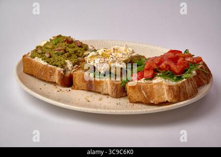 Eine Auswahl an köstlichen, offenen Sandwiches mit einzigartigen Belägen wie Avocado, Cream Cheese und frischem Gemüse auf Toast Stockfoto