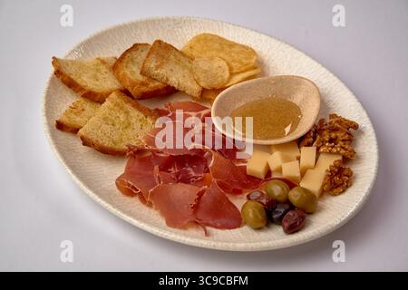Eine wunderschön gestaltete Platte mit einer Auswahl an Aufschnitt, Käse und Snacks, perfekt für ein elegantes Treffen oder ein ungezwungenes kulinarisches Erlebnis Stockfoto