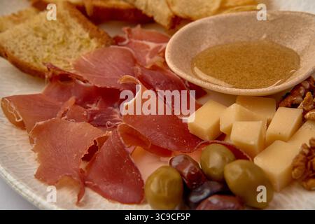 Eine köstliche Charcuterie Board mit Räucherfleisch, verschiedenen Käsesorten, Honig, Nüssen und handwerklichem Brot für ein perfektes Verkostungserlebnis Stockfoto