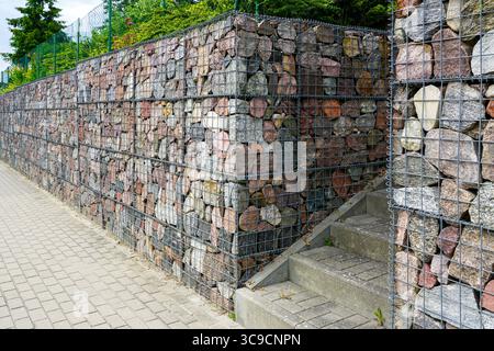 Gabionen Stützmauern mit bunten Steinen säumen eine Betontreppe in einem gestalteten städtischen Gehweg Stockfoto