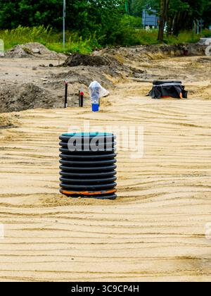 Inspektionskammer aus Wellkunststoff auf einer sandigen Baustelle mit sichtbaren Graben und Gebrauchselementen. Stockfoto