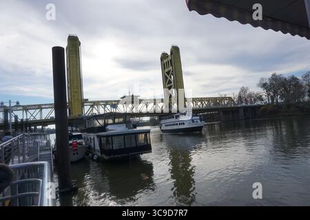 Ausflugsboote und Hausboote legen entlang des Sacramento River mit der berühmten gelben Tower Bridge im Hintergrund an Stockfoto