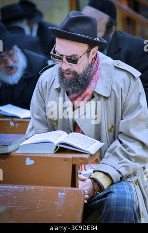 Ein Mann in einer Synagoge, der sowohl Sonnenbrille als auch Lesebrille trägt. Während der Gottesdienste in einem Tempel in Brooklyn, New York im Jahr 2014. Stockfoto