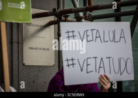 BRASILIANISCHE BOTSCHAFT, LONDON, Großbritannien – 05. August 2025: Demonstranten versammeln sich vor der brasilianischen Botschaft und rufen Präsident Lula auf, gegen das sogenannte „Verwüstungsgesetz“ zu verstoßen, das angeblich die Rechte der Indigenen bedroht, den Umweltschutz schwächt und die Entwaldung im Amazonasgebiet beschleunigt. Der von Brazil Matters organisierte Protest nutzte Lärm, Banner und symbolische Aktionen, um die Aufmerksamkeit auf die potenziellen Auswirkungen des Gesetzes auf die biologische Vielfalt, die indigenen Gemeinschaften und das globale Klima zu lenken. Stockfoto