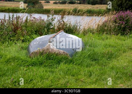 Altes umgedrehtes Ruderboot am verwachsenen Ufer eines ländlichen Sees Stockfoto