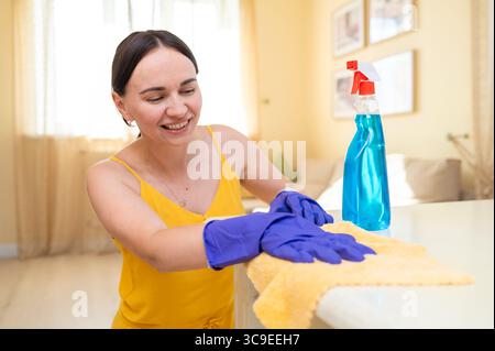 Junge, schöne Hausfrau, Poliertisch mit Lappen Stockfoto