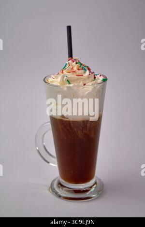 Ein köstlich cremiges Eiskaffee-Getränk mit Schlagsahne und bunten Sprenkeln in einer Klarglasschale, perfekt für kalte Leckereien Stockfoto
