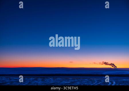 31. Dezember 2021, Alberta, Kanada: Die Aufstellung von vier Planeten in der Abenddämmerung am Silvesterabend, 31. Dezember 2021, und in einer sehr kühlen Nacht mit einer Temperatur von -25Â C. somit der Dampf aus dem fernen Kraftwerk. ..der Quecksilber stieg höher in Richtung seiner größten Dehnung am 7. Januar 2022, während die Venus niedriger in Richtung ihrer unterlegenen Verbindung mit der Sonne am 9. Januar abfiel. Sie gingen in dieser Nacht an einander vorbei und waren so in fast derselben Höhe tief im Südwesten. Jupiter (links oben) und Saturn (Mitte) fielen ebenfalls jede Nacht nach unten, um auch nahe der Sonne zu verschwinden Stockfoto