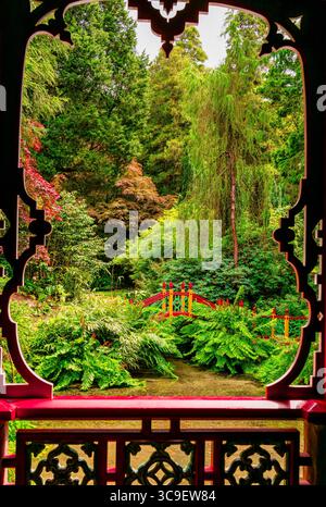 Blick durch den kunstvollen Pavillon Frame auf den üppigen chinesischen Garten und die Rote Brücke Stockfoto