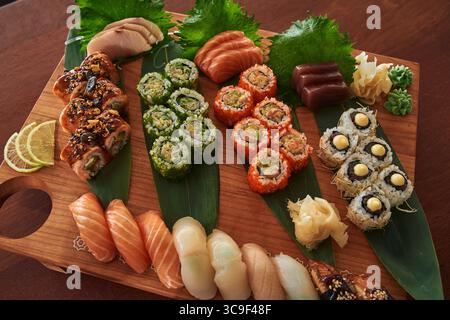 Eine lebendige Sushi-Platte mit einer Auswahl an frischen Gerichten, darunter Rolls, Sashimi und bunte Pflaster auf einem Holzbrett Stockfoto