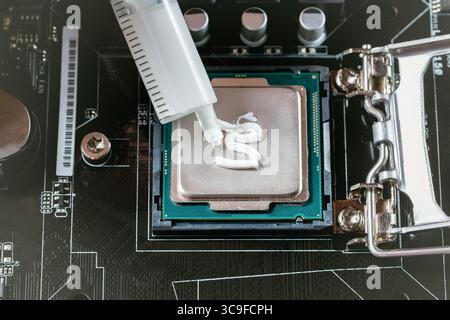 Auftragen von Wärmeleitpaste während der CPU-Installation in der Nähe auf der Hauptplatine. Stockfoto