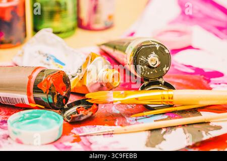 Malerarbeitsplatz mit mehrfarbigen Ölfarben und Pinseln auf lackiertem Papier in Nahaufnahme. Stockfoto