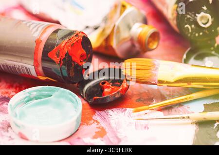 Malerarbeitsplatz mit mehrfarbigen Ölfarben und Pinseln auf lackiertem Papier Nahaufnahme mit selektivem Fokus. Stockfoto