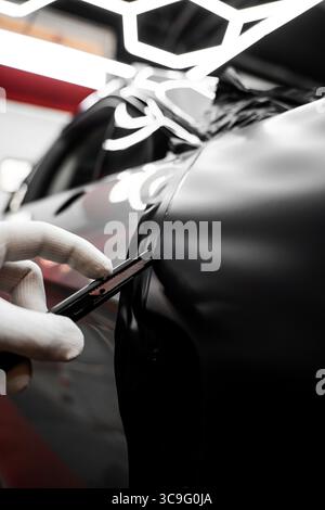 Die Anwendung „Auto Wrap“ ändert das Erscheinungsbild des Fahrzeugs. Vinyl-Verpackung Für Autos Mit Vollpaneel. Die großformatige Vinylfolie verwandelt das Außendesign des Fahrzeugs Stockfoto