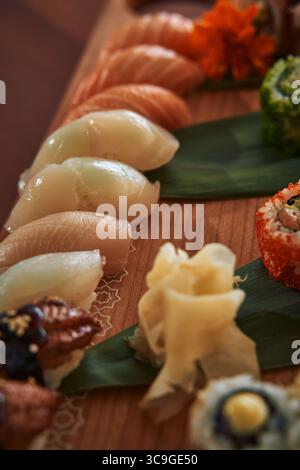 Eine kunstvolle Auswahl an Sushi-Köstlichkeiten mit einer Vielzahl von frischem Fisch und farbenfrohen Zutaten serviert auf einer schönen Holzplatte Stockfoto
