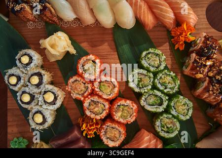 Eine exquisite Auswahl an bunten Sushi Rolls und Köstlichkeiten, kunstvoll präsentiert auf einem Holzteller, garniert mit frischen Zutaten Stockfoto