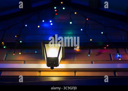 Leuchtende bunte Weihnachtslichter und Lampe am Hauseingang. Stockfoto