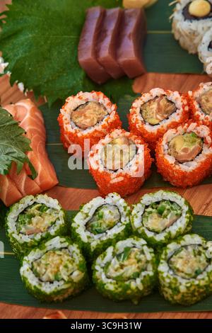 Ein farbenfrohes Sortiment an Sushi Rolls mit frischen Zutaten und abwechslungsreichen Aromen, kunstvoll auf einem Holzbrett präsentiert Stockfoto