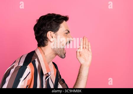 Porträt eines jungen Mannes in einem gestreiften Hemd auf rosafarbenem Hintergrund, der mit seiner Hand Gesten zeigt, als ob er spricht Stockfoto