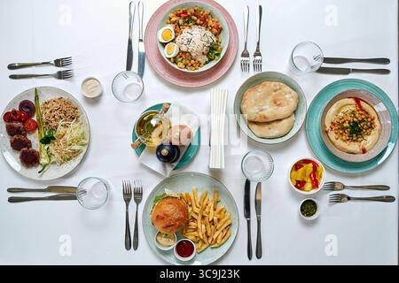 Eine lebendige Auswahl an Gerichten mit verschiedenen Aromen und Texturen, darunter Reis, Salate, Hummus und Vorspeisen, die kunstvoll auf Tellern zubereitet werden Stockfoto