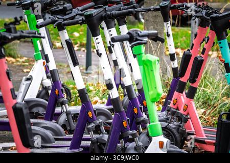 Nahaufnahme von Reihen bunt bemalter dockloser Elektroroller, die auf einer Straße in Düsseldorf geparkt sind und die moderne gemeinsame Mikromobilität und -Mobilität veranschaulichen Stockfoto