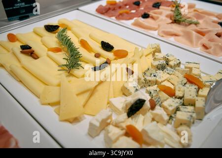 Eine wunderschön angeordnete Käse- und Wurstplatte mit verschiedenen Käsesorten, getrockneten Früchten, Nüssen und frischen Kräutern für ein einladendes Gourmet-Erlebnis Stockfoto