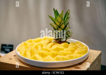 Eine frisch geschnittene Ananas auf einem weißen Teller mit saftig gelben Fruchtstücken zum Genuss Stockfoto