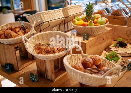 Ein wunderschön gestaltetes Frühstücksangebot mit verschiedenen Brotsorten, frischem Obst und Gebäck in handwerklichen Körben, umgeben von einem gemütlichen Ambiente Stockfoto