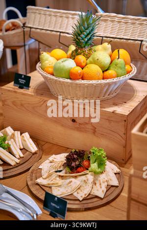 Eine lebhafte Auswahl an frischem Obst und Gemüse, elegant in einem gewebten Korb präsentiert, ergänzt durch eine ordentlich angeordnete Platte mit Tortillas und Stockfoto
