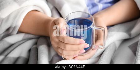 Frau mit einer Tasse leckeren blauen Schmetterlingserbsenblüten-Tee zu Hause, Nahaufnahme Stockfoto