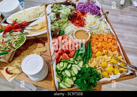 Bunte Auswahl an frischem Gemüse, Obst und Salaten auf einem Holzteller, perfekt für gesunde Ernährung und lebendige kulinarische Präsentationen Stockfoto