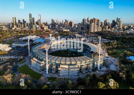 Der Melbourne Cricket Ground MCG ist bei Sonnenaufgang vor der Skyline von Melbourne City zu sehen. Stockfoto