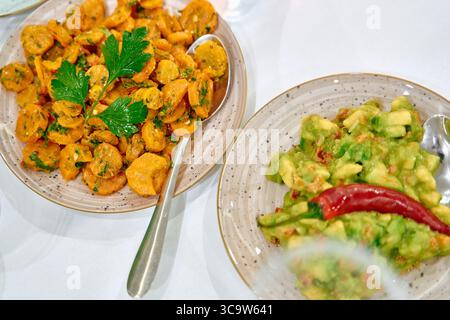 Eine bunte Auswahl köstlicher Gerichte auf Pflanzenbasis mit gewürzten Karotten und Avocado-Salat garniert mit frischen Kräutern und Chili-Paprika Stockfoto