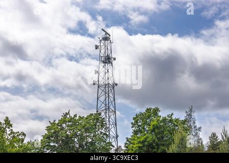 Mobilfunkturm aus Stahl, der über grünen Bäumen ragt Stockfoto