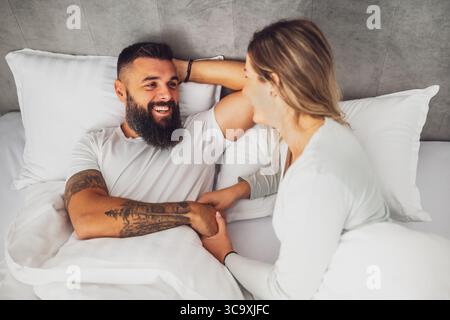 Ein glückliches Liebespaar liegt morgens im Bett. Sie sind entspannend und lächeln. Stockfoto