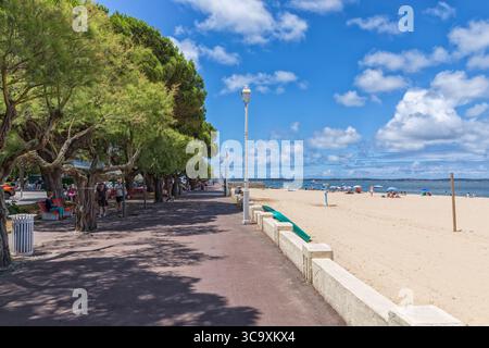 Arcachon, Frankreich – 26. Juni 2025: Die von Tamarix-Bäumen gesäumte Promenade und der Stadtstrand am Arcacon Basin an einem sonnigen Sommertag. Stockfoto