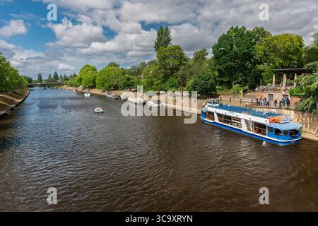 Bootstour auf dem Fluss Ouse in York, England, an einem sonnigen Tag, mit festgefahrenen Schiffen, Grün am Fluss und sichtbaren Außencafés. Stockfoto