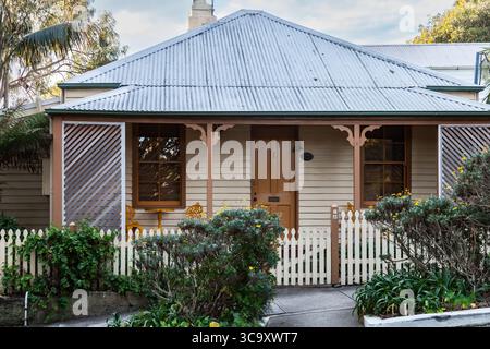 Camp Cove, Watsons Bay, Sydney, Australien. 26. August 2025. Ein kleines Weatherboard Cottage hinter dem Strand in Camp Cove. Auch bekannt als Fischerhütten, einige stammen aus der Mitte des 19. Jahrhunderts. Die Blechdächer auf den kleinen Cottages in Camp Cove sind ein charakteristisches Merkmal ihres historischen und küstennahen Charmes. Stockfoto