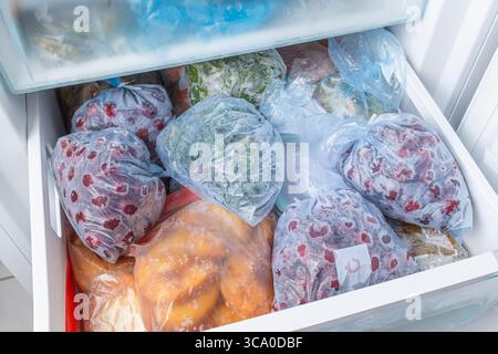 Gefrorenes Obst und Gemüse in Kunststoffbeuteln im Gefrierschrank mit frostfreiem Haushaltskonzept Stockfoto