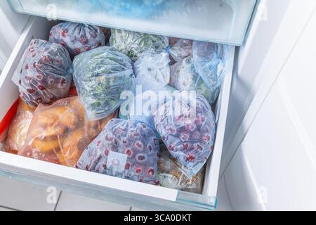 Gefrorenes Obst und Gemüse in Kunststoffbeuteln im Gefrierschrank mit frostfreiem Haushaltskonzept Stockfoto