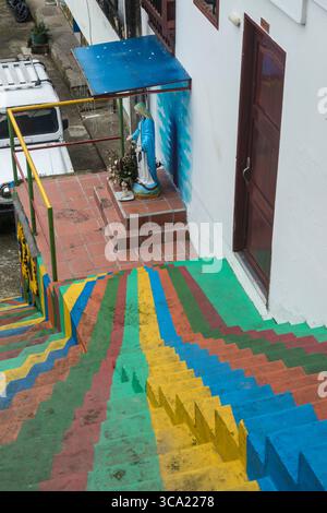 Mehrfarbige Linien auf Treppen, die an einer Marienstatue unter einem Baldachin in einem Haus in Guatapé, Antioquia Department, Kolumbien, zusammenkommen Stockfoto